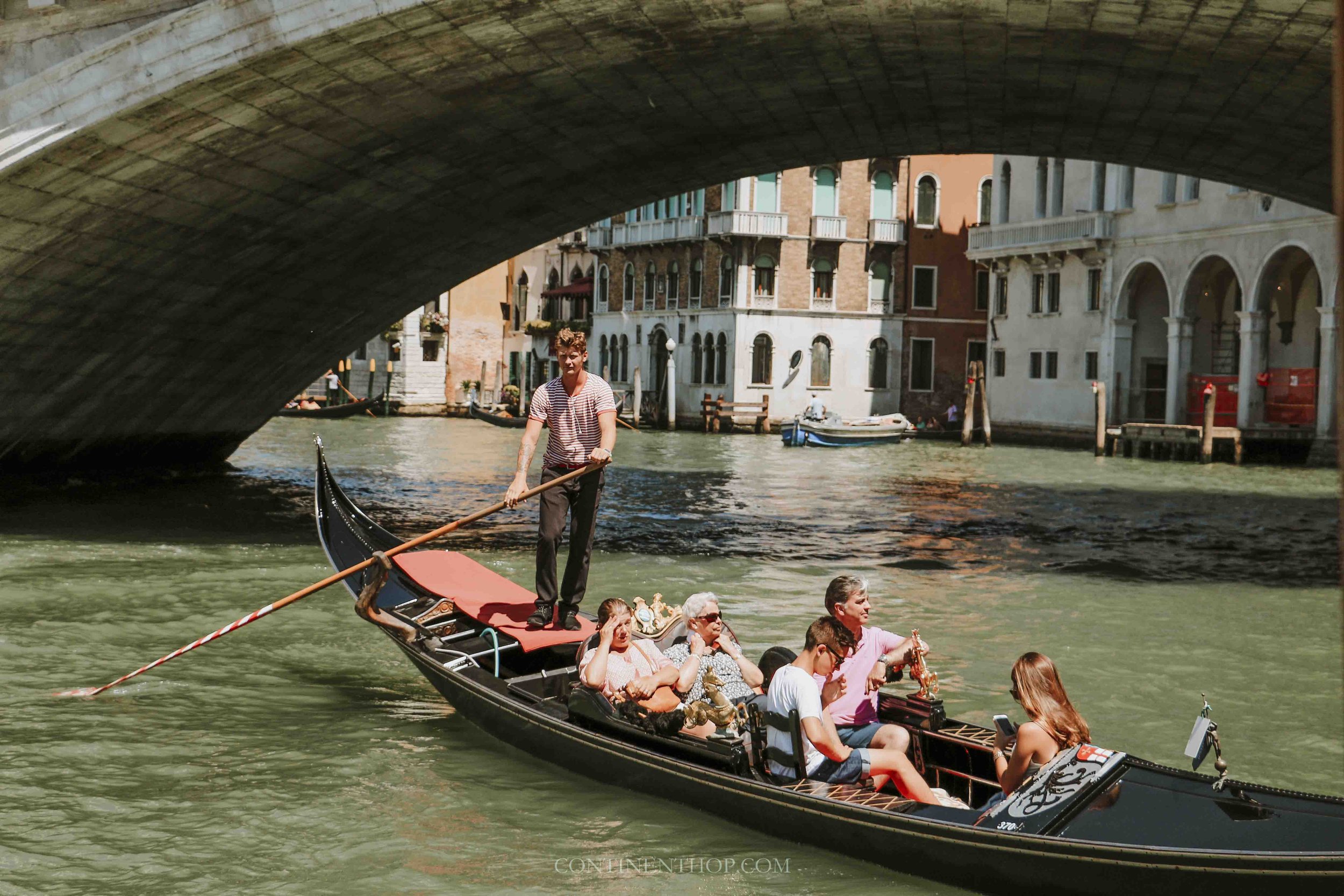 A gondola passing under rialto bridge on a 2 day itinerary venice italy