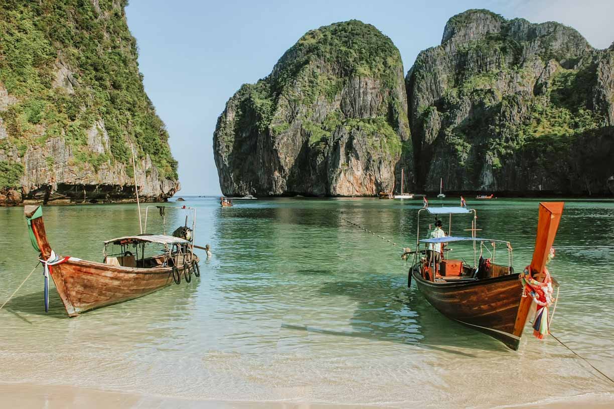 Colourful boats moored to shore at James Bond island on a 7 days in Phuket itinerary