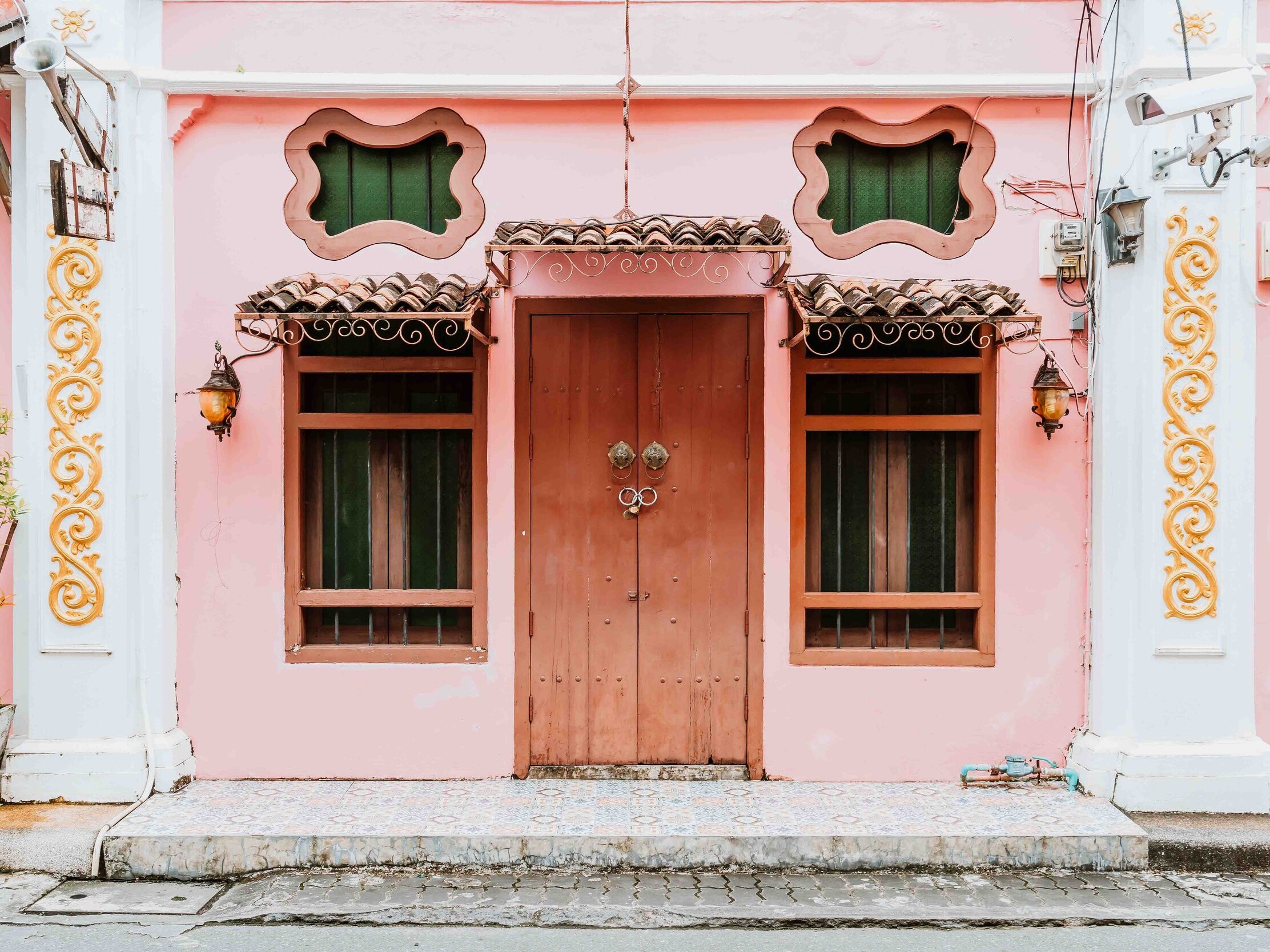 A pretty pink building with a brown door in phuket old town on an itinerary for phuket