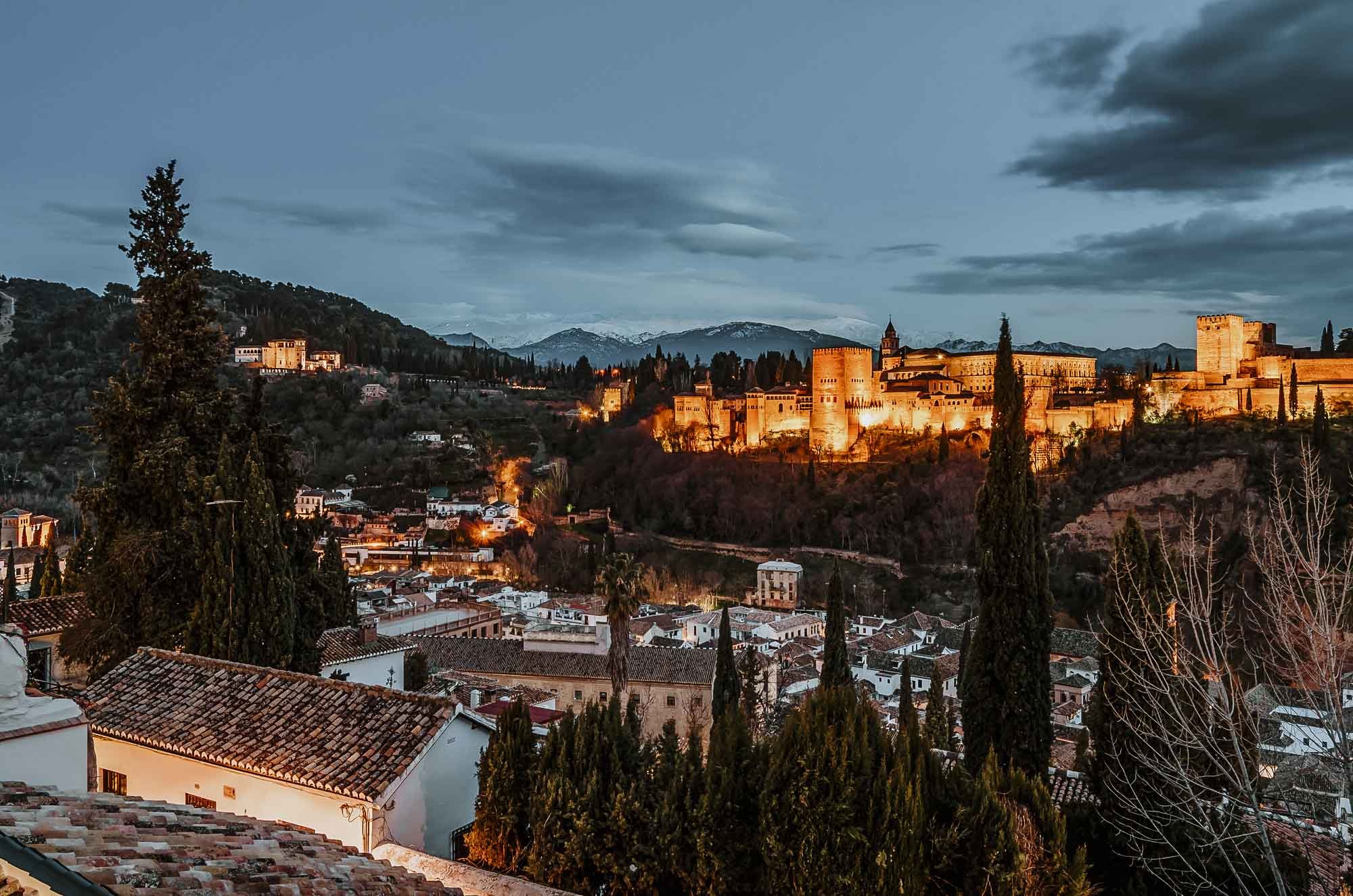 The Alhambra by night all lit up with the Albaicin neighborhood on the side