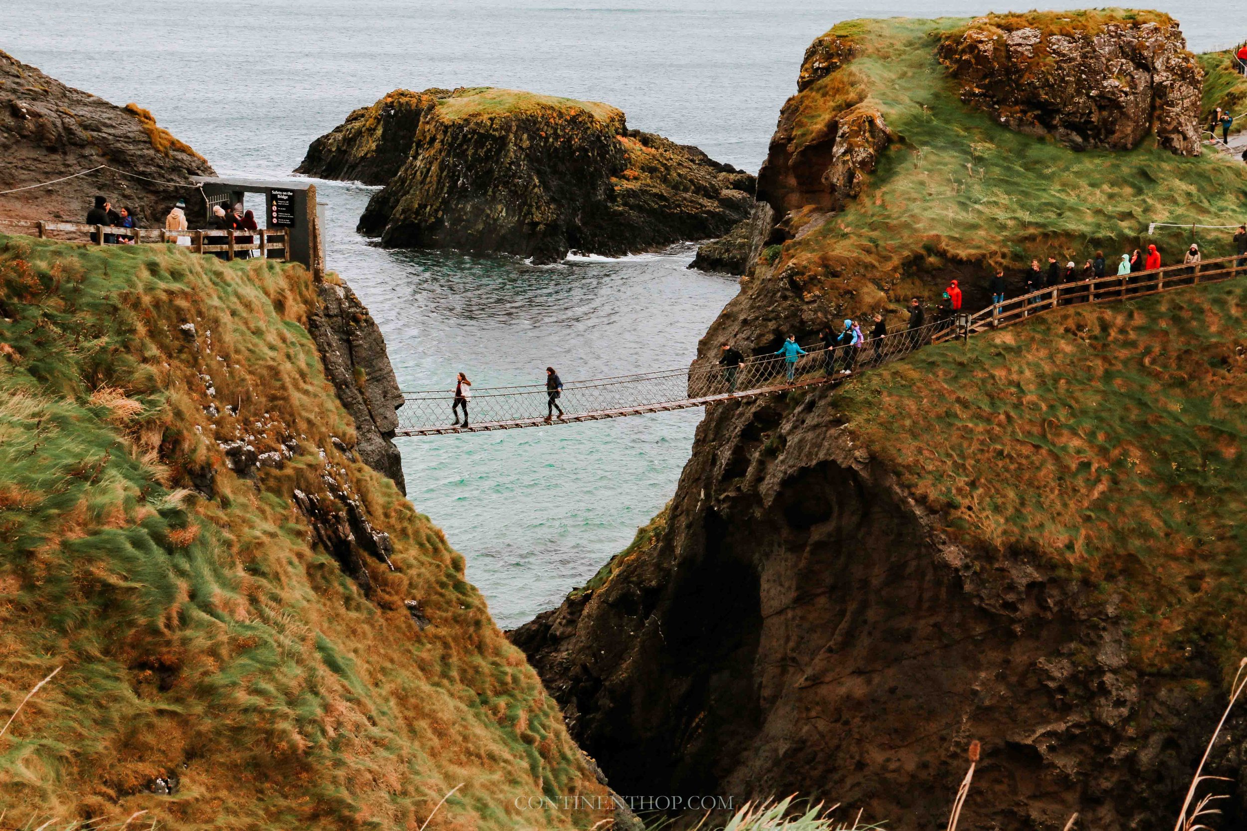 People crossing carrick a rede rope bridge from belfast to giants causeway