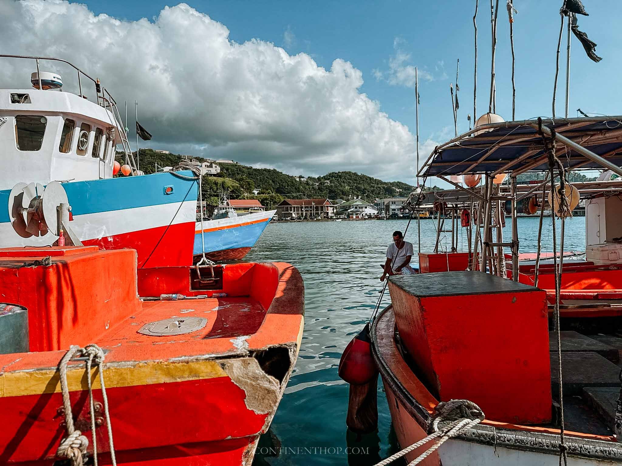 Man working on a colourful boat by marina in December best time of year to go to Grenada