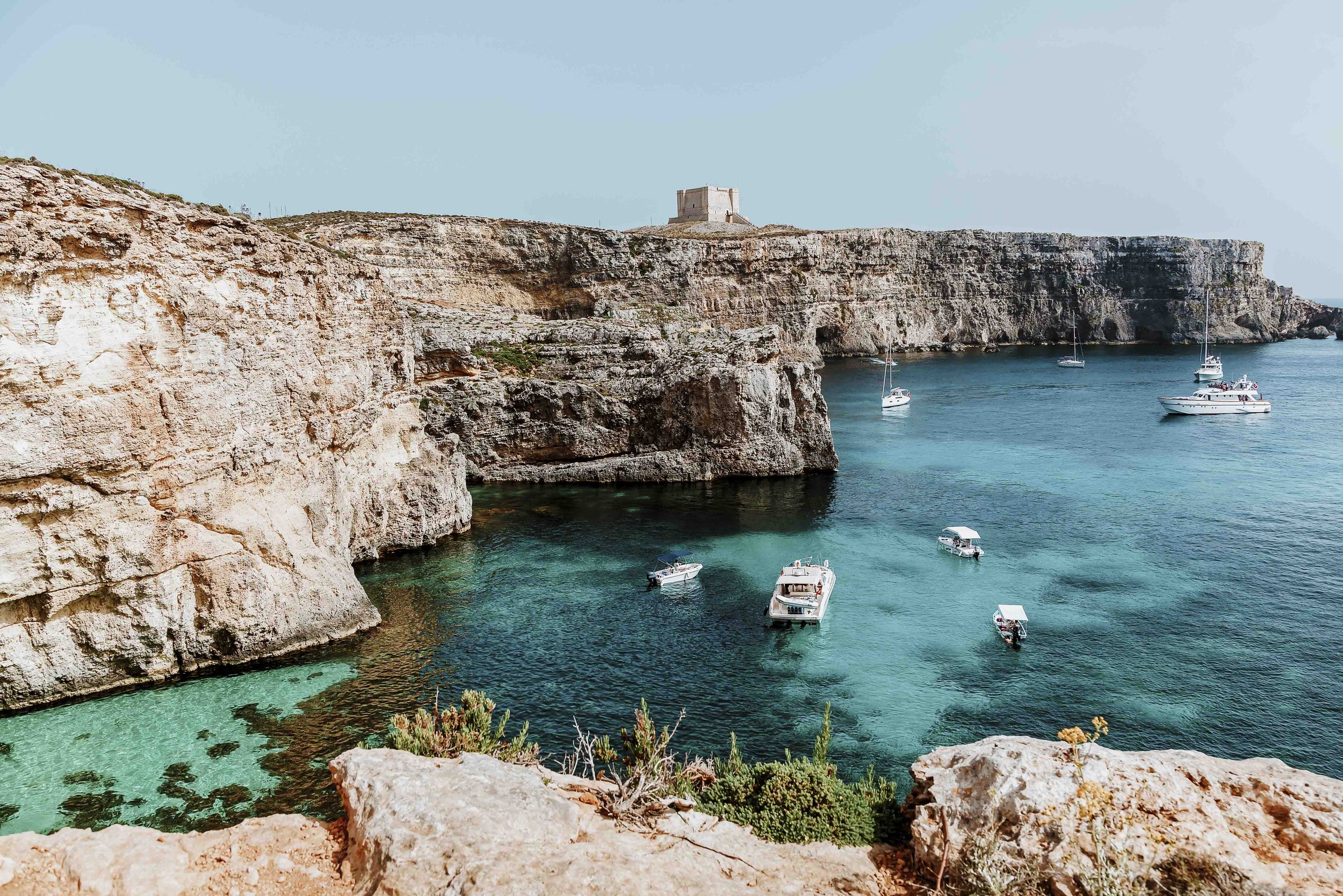 Boats cliffs and sea caves near the blue lagoon malta comino blue lagoon