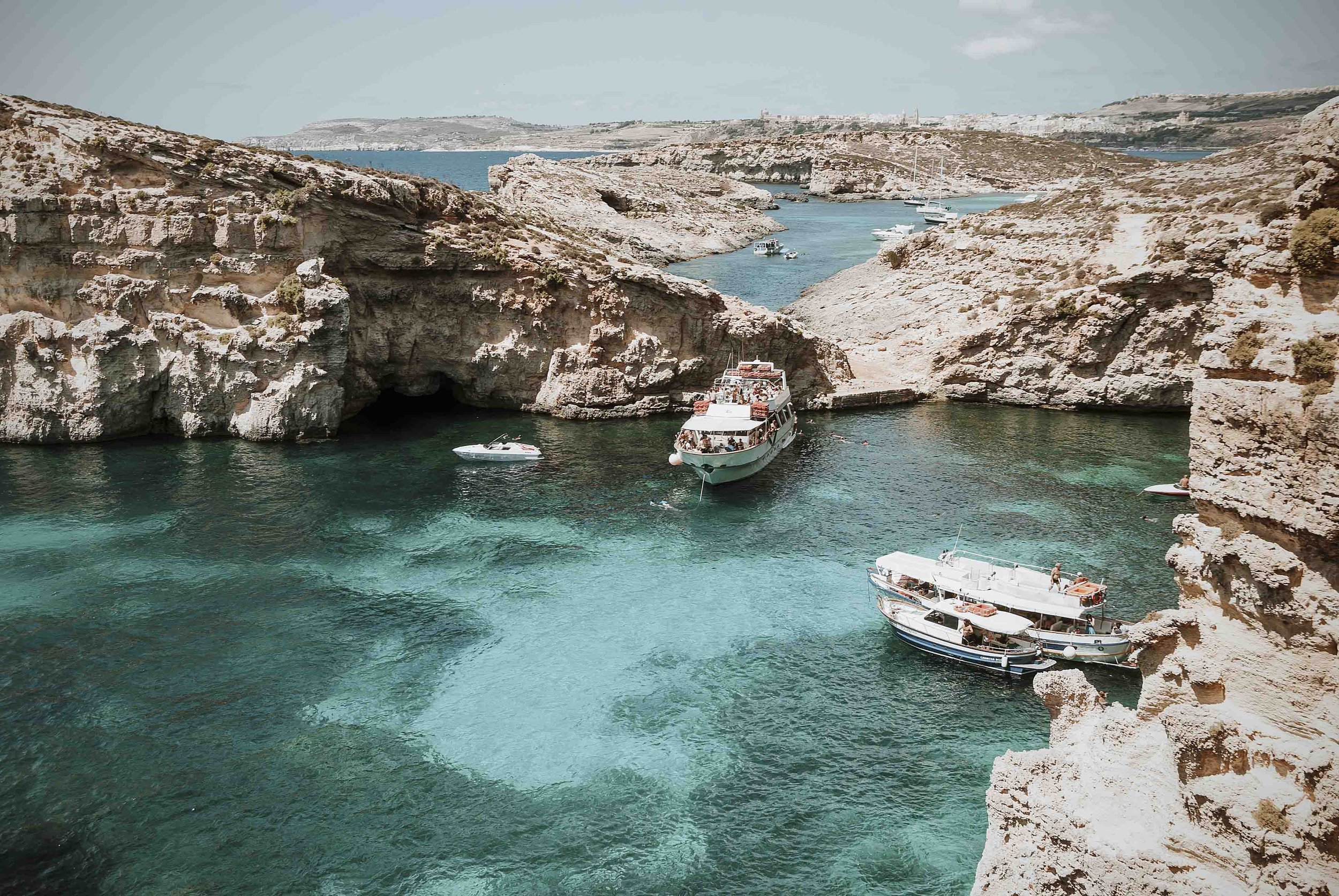 Boats cliffs and caves near the blue lagoon comino malta