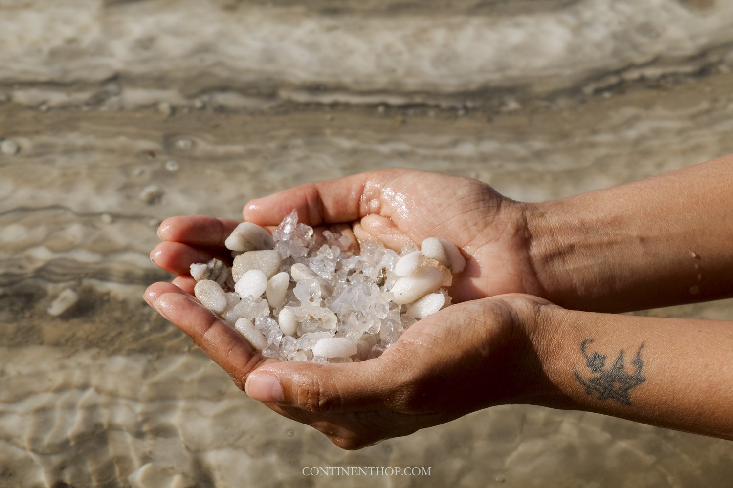 Woman holding dead sea salt while floating on the dead sea