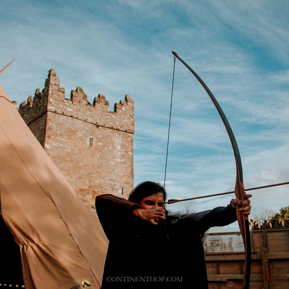 Woman shooting an arrow in front of tepee on a GOT locations in Northern Ireland visit
