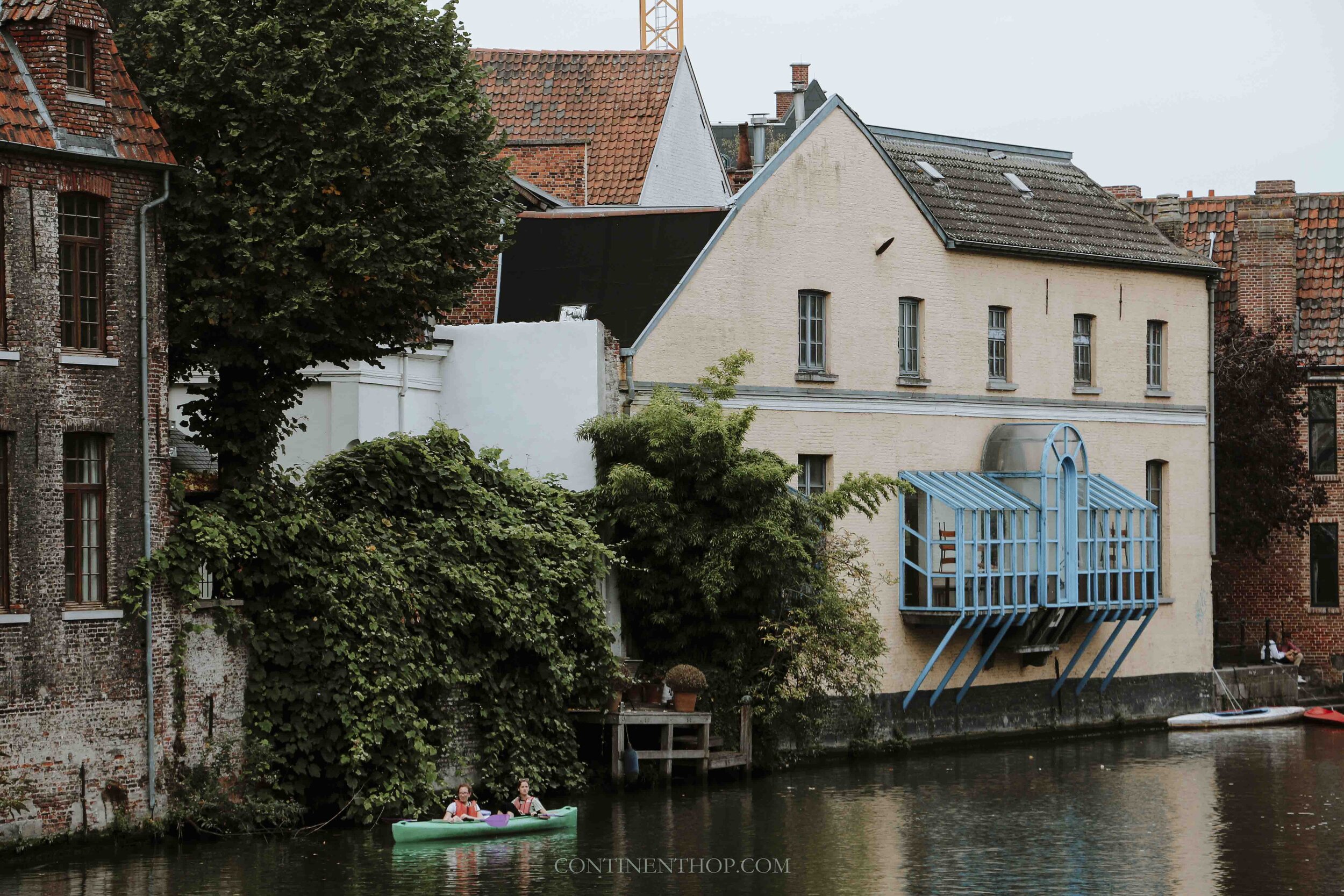 People canoeing in the river Leie in Ghent passing through colorful houses
