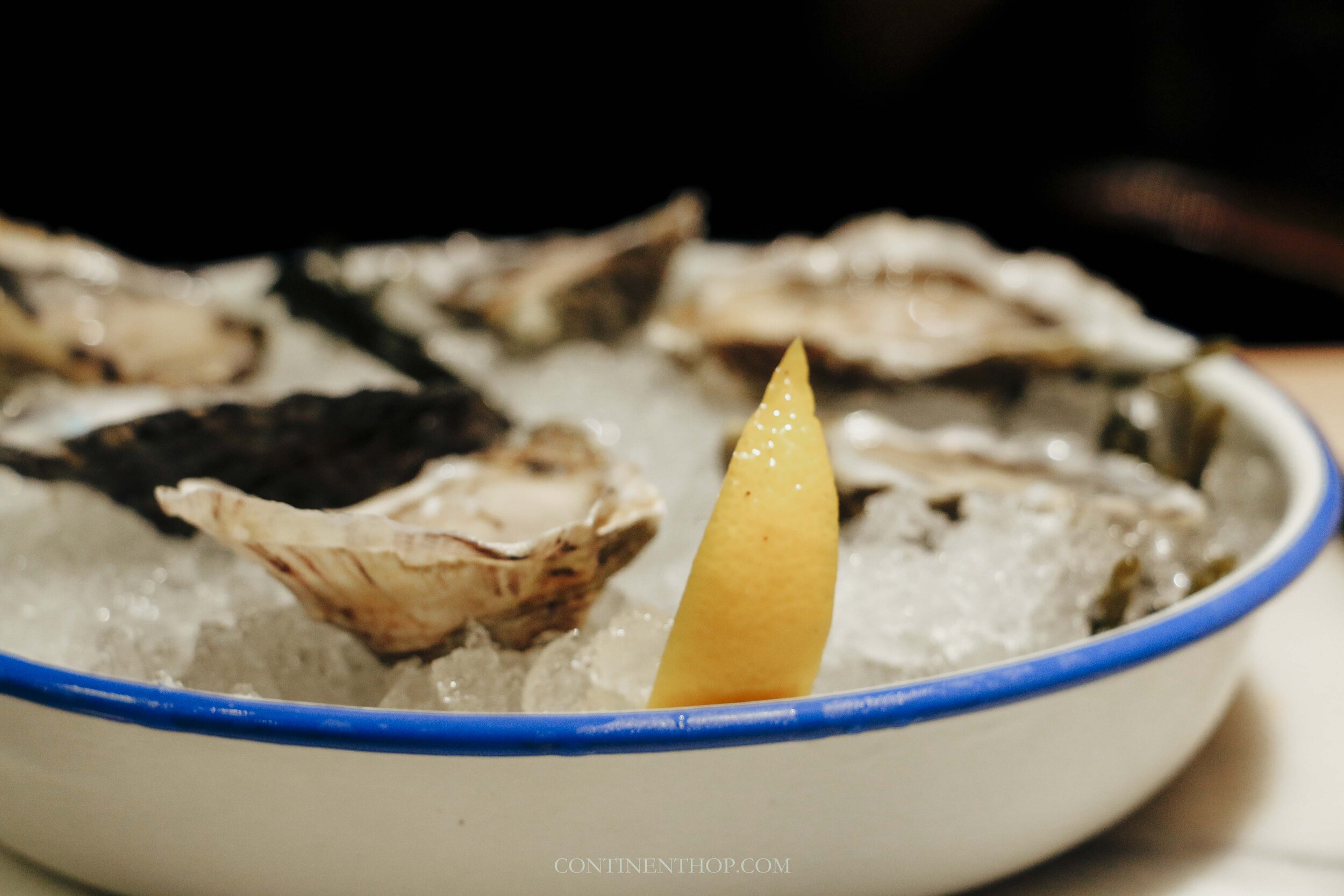 A bowl with fresh oysters on ice and a slice of lemon in Gent