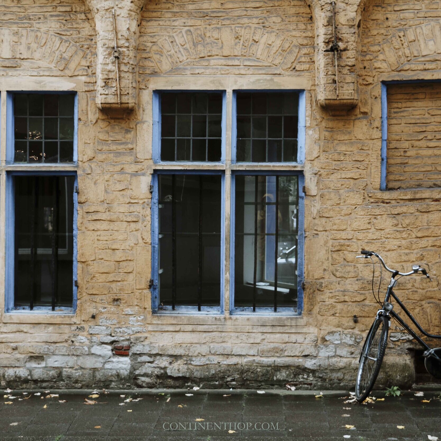 A bicycle leaning on a yellow wall in Gent