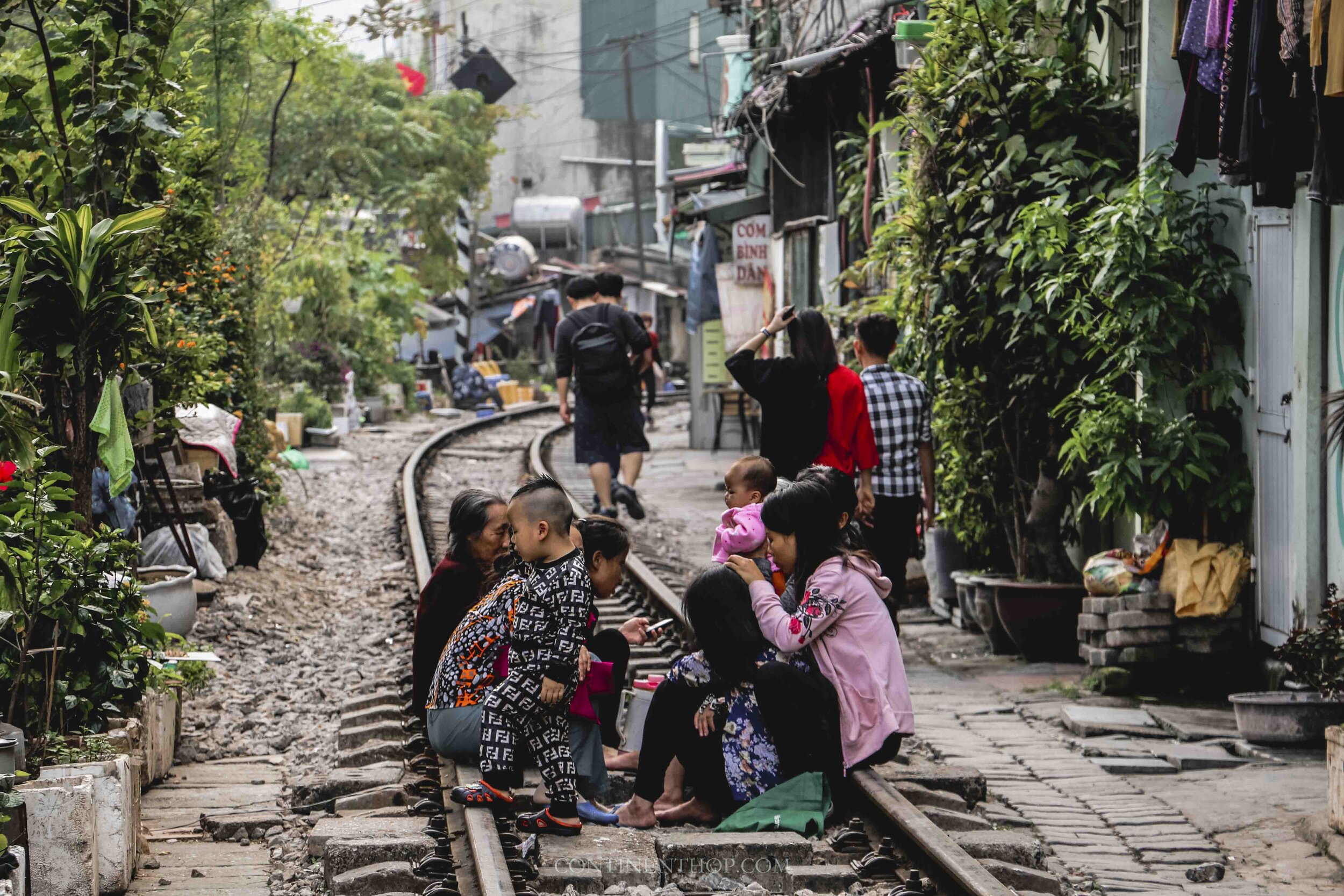 Image of people in Hanoi Vietnam sitting on a train track chatting