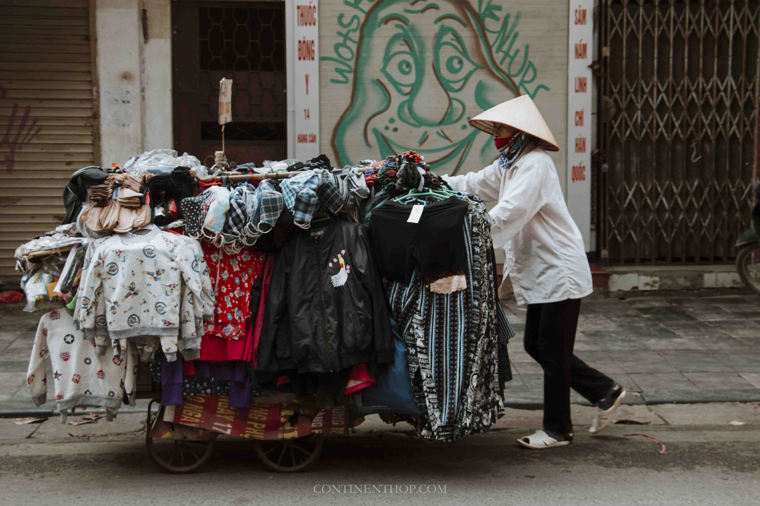 Image of Woman in Hanoi Vietnam pushing a cart full of clothes