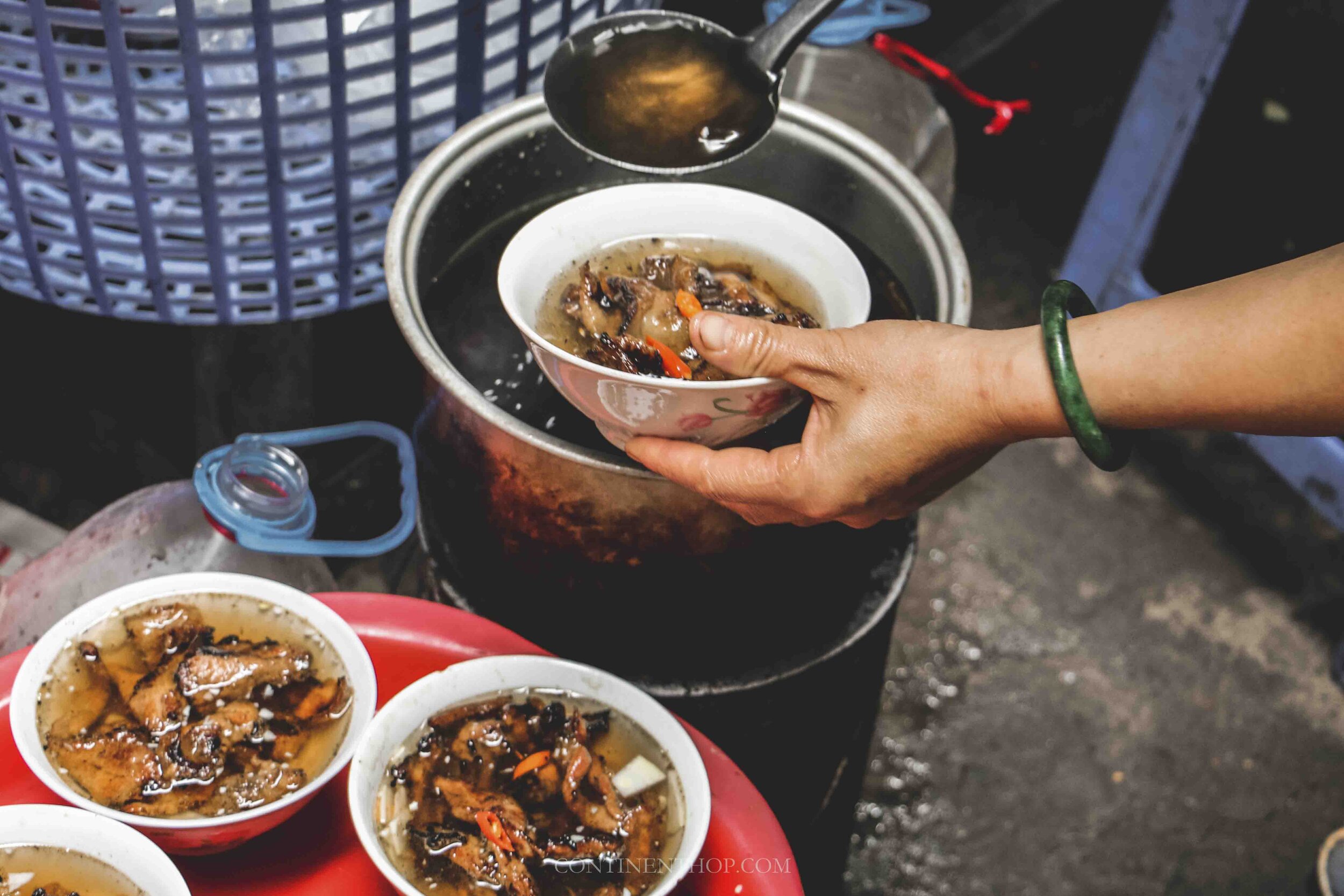 Image of woman pouring bun cha soup in a bowl in Hanoi Vietnam