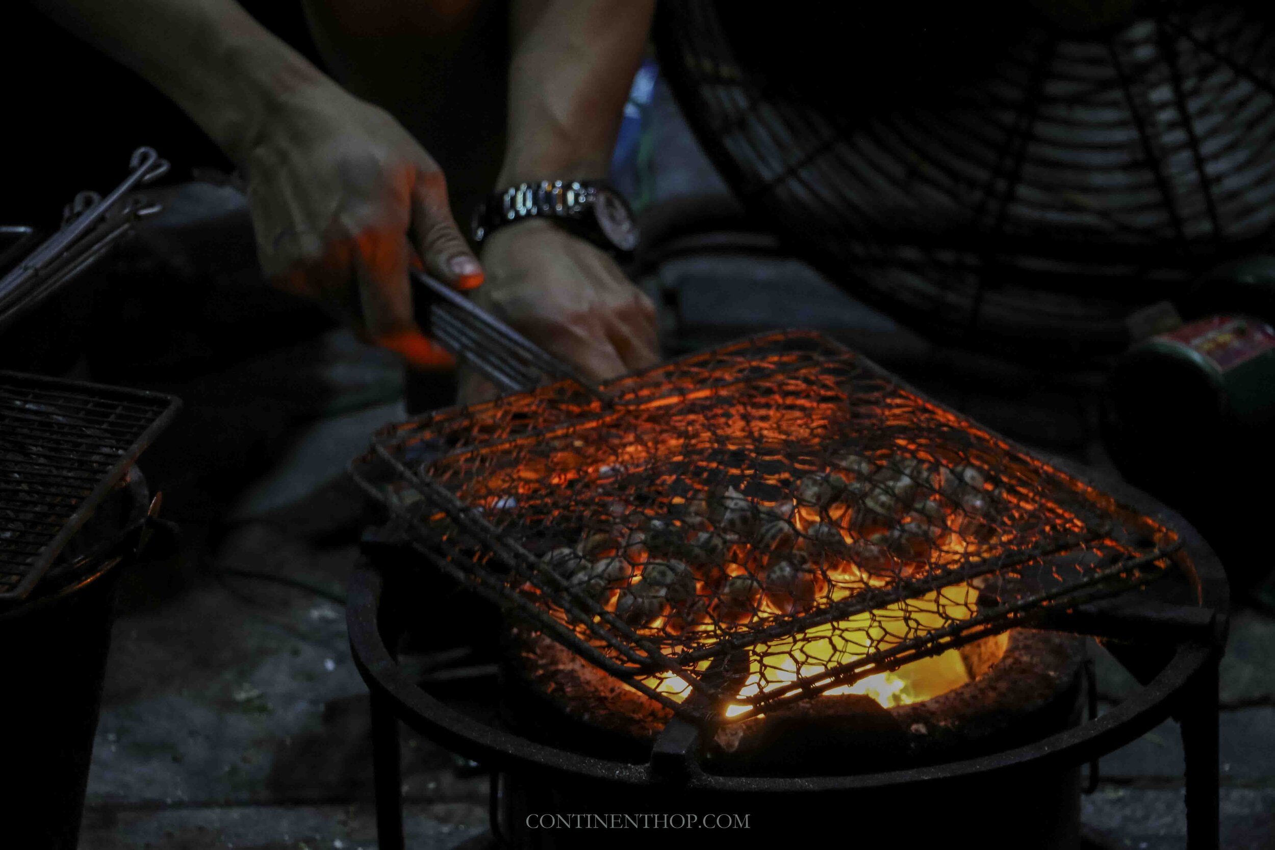 Image of man grilling snails on coals in Hanoi Vietnam