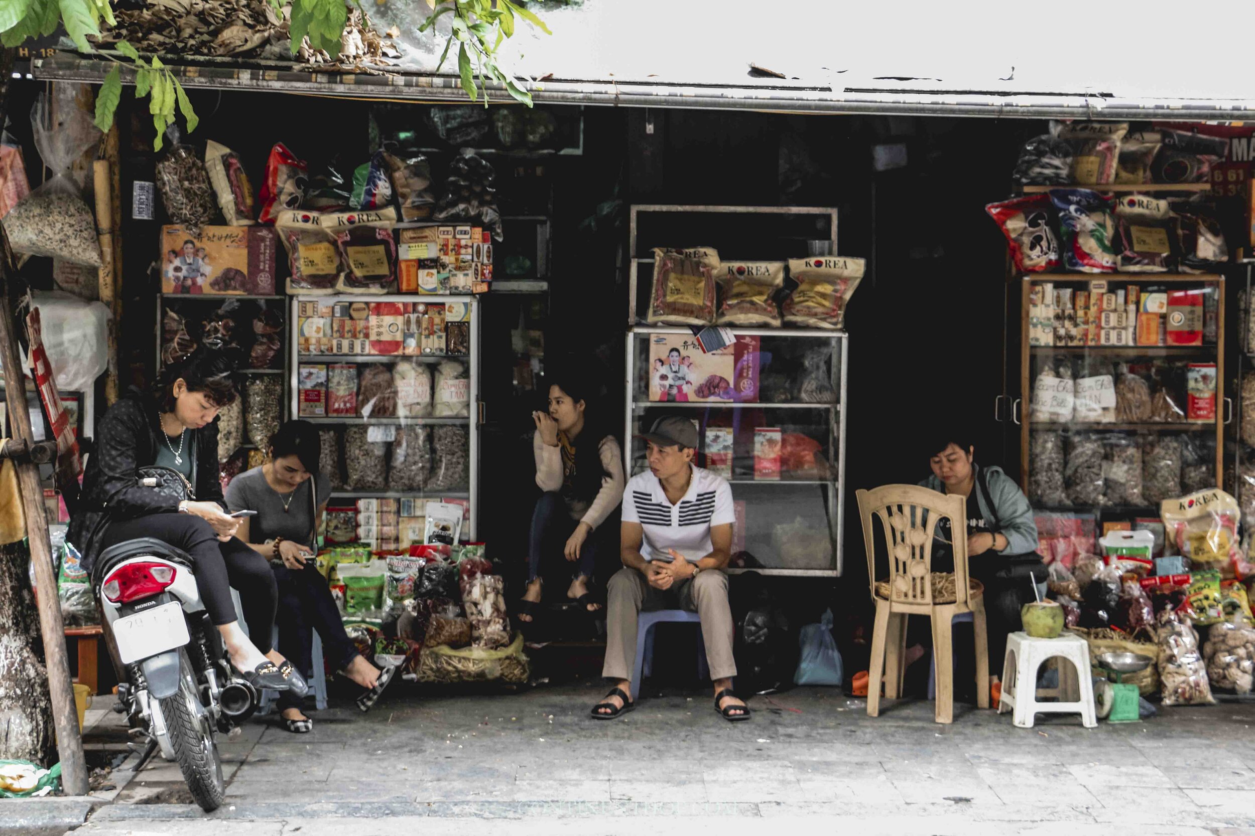 Photo of people in Hanoi Vietnam sitting outside a shop people watching