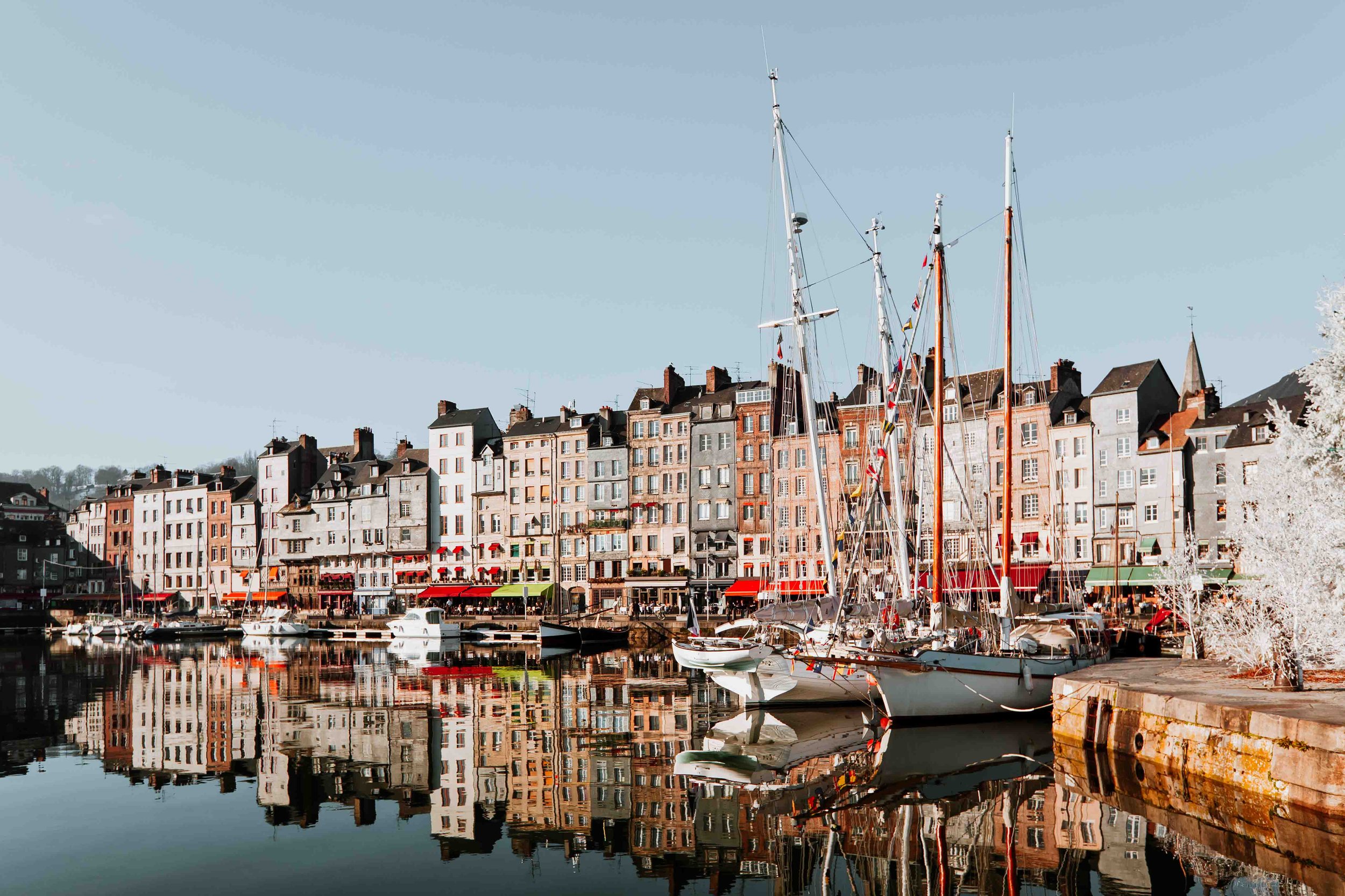 Colourful boats and houses by the marina in Honfleur on a road trip to Normandy itinerary