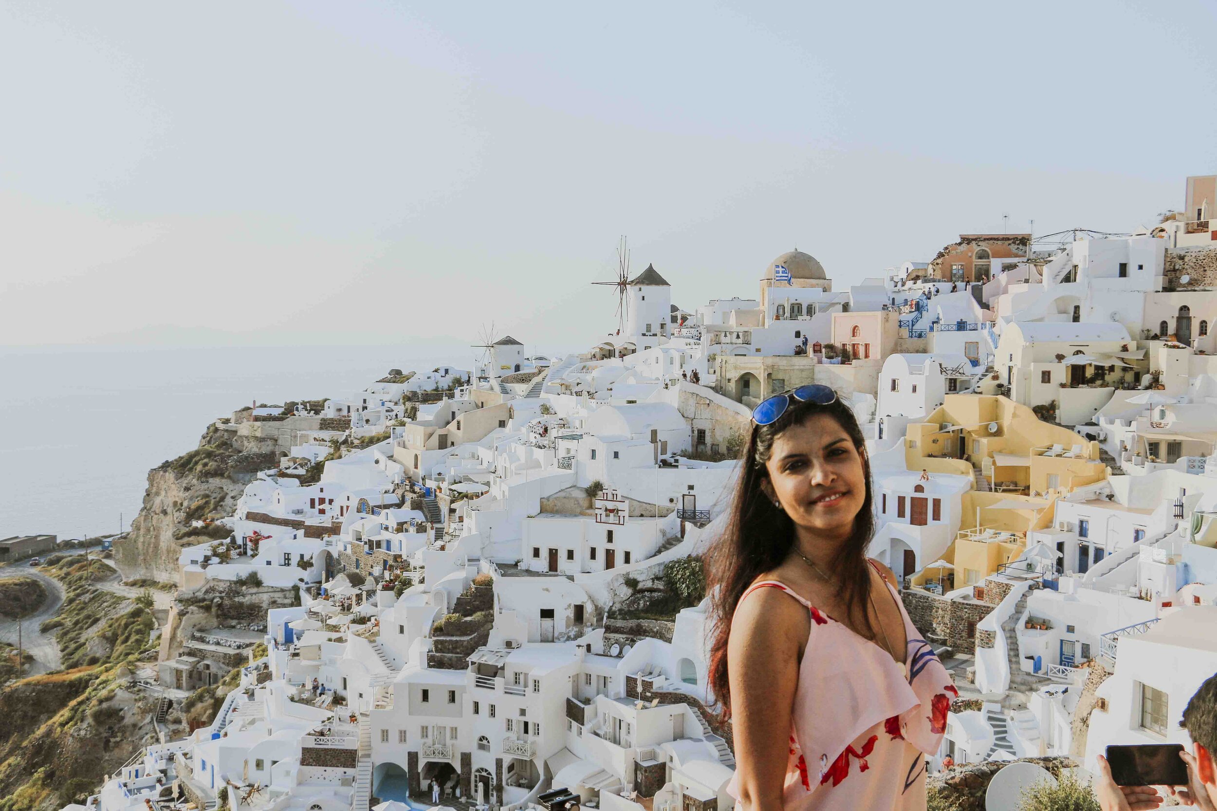 Woman smiling while standing in front of Oia in Santorini