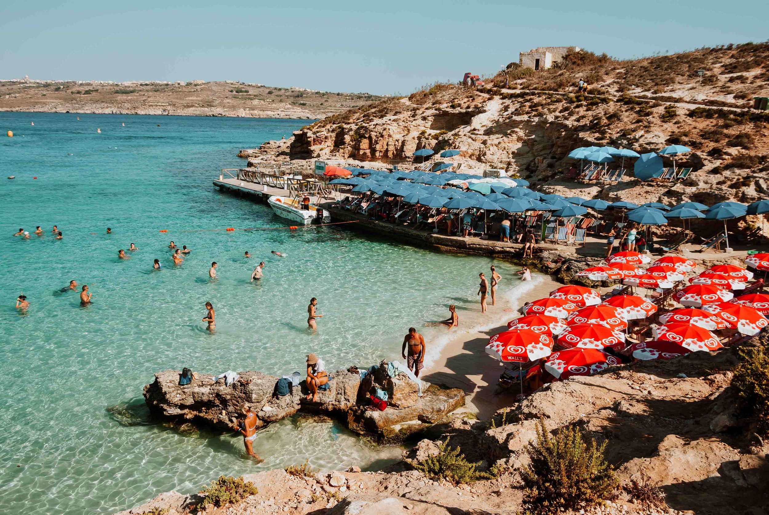 People swimming on the beach in Blue Lagoon Malta one of the Warmest places in Europe in April
